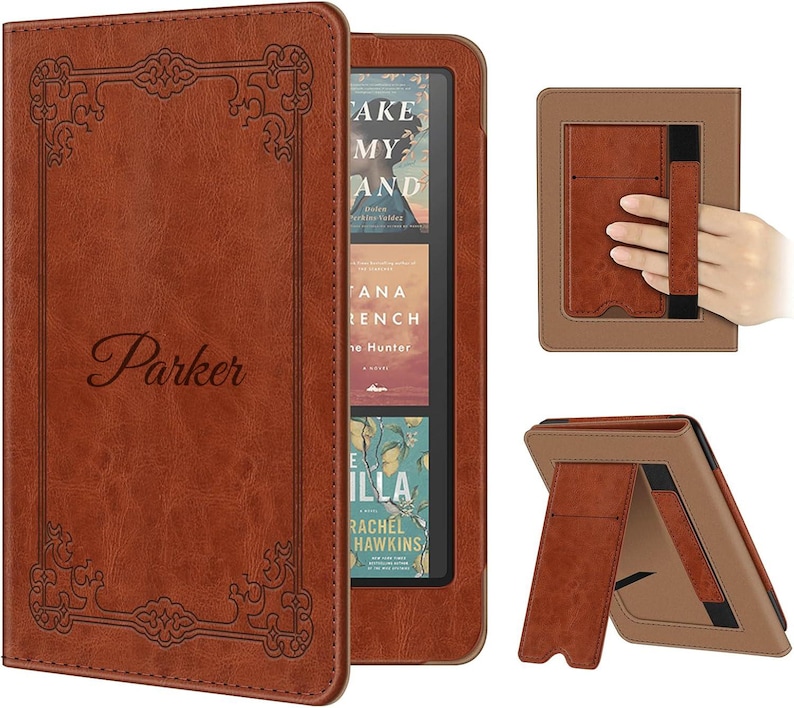 May include: A brown leather-like e-reader case featuring an embossed decorative border and the name Parker in script. The case includes a built-in stand and an elastic hand strap on the back, designed to hold an e-reader device securely.