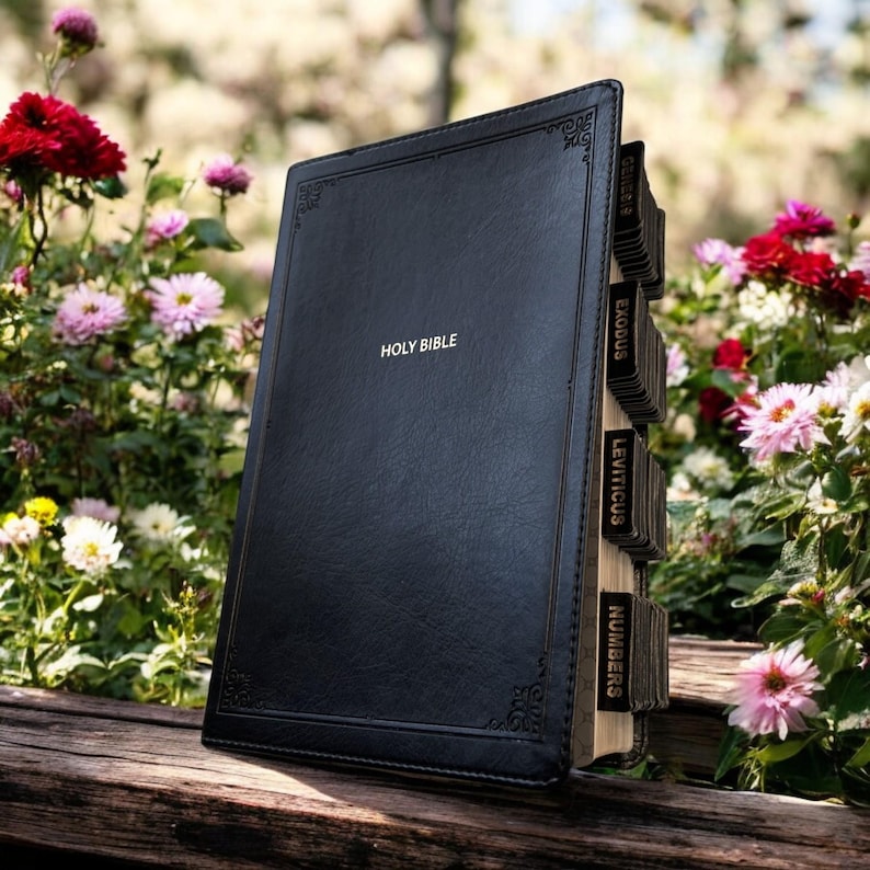 Peut inclure: Une Sainte Bible en cuir noir avec des lettres dor&eacute;es. Le livre est ouvert, r&eacute;v&eacute;lant des onglets &eacute;tiquet&eacute;s pour diff&eacute;rents livres de la Bible. L'arri&egrave;re-plan pr&eacute;sente des fleurs et de la verdure color&eacute;es, cr&eacute;ant un cadre serein.