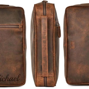 Pu&ograve; includere: Set di tre borse in pelle marrone. Le borse hanno una finitura invecchiata e una chiusura con cerniera. Una borsa ha il nome "Michael" in rilievo. Le borse hanno un manico e una tracolla.
