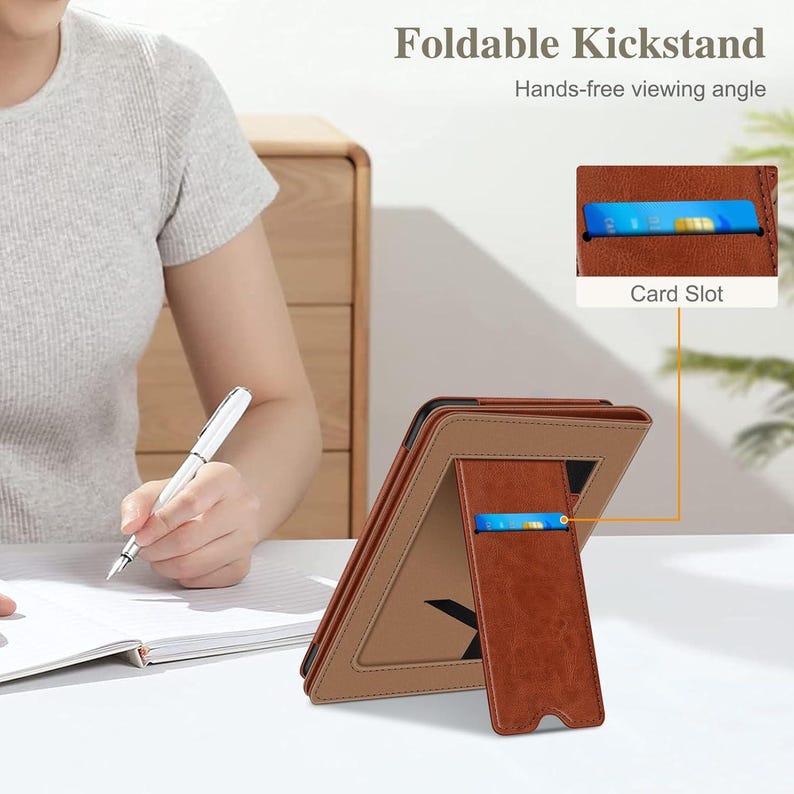 May include: A brown faux leather tablet case featuring a foldable kickstand for hands-free viewing and an integrated card slot. The case has a textured finish and a tan border, with a blue card visible in the slot. The text reads Foldable Kickstand.