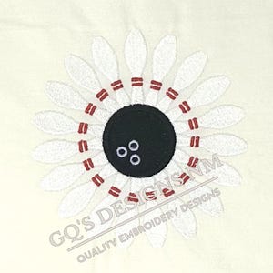 May include: White bowling pins arranged in a circle around a black bowling ball with three red dots. The text "GQ'S DESIGNS NM" and "QUALITY EMBROIDERY DESIGNS" is below the bowling pins.
