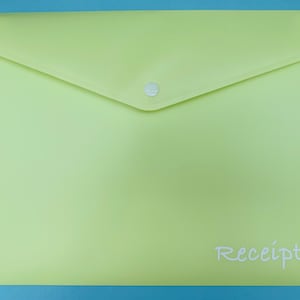 May include: A pale green plastic envelope with a button fastening. The word "Receipts" is written in cursive on the lower right corner. The envelope is on a blue background.