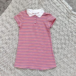 May include: A short-sleeved, striped polo dress in red, white, and purple. The dress features a white collar and a button-down placket. The fabric has horizontal stripes. The dress is likely for children.