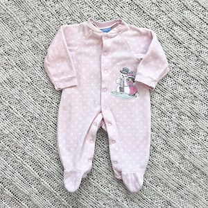 Può includere: Tutina rosa per neonati con pois bianchi e grafica a pupazzo di neve. La tutina intera ha maniche lunghe, piedini coperti e un'abbottonatura frontale. La grafica presenta un pupazzo di neve e una donna delle nevi.