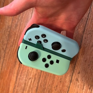 Könnte beinhalten: Ein hellblauer und grüner Nintendo Switch-Controller mit schwarzen Knöpfen.