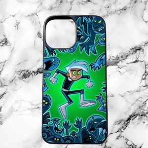 May include: A black phone case featuring a green background with a cartoon image of a ghost character with blue eyes and a white face. The ghost is surrounded by other ghost characters in blue and black.