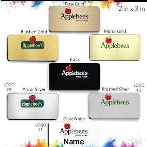 May include: Applebee's name badge design options in various colors and finishes, including rose gold, brushed gold, mirror gold, black, mirror silver, brushed silver, and gloss white. The badges are 2 inches by 3 inches and feature the Applebee's logo and the text "GRILL + BAR".