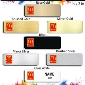 May include: A set of eight different name badges featuring the McDonald's logo in red and yellow. The badges are available in brushed gold, mirror gold, black, mirror silver, brushed silver, and gloss white. Each badge is 1 inch by 3 inches.
