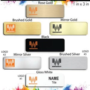 May include: A set of 10 Whataburger name badges in various colors and finishes, including rose gold, brushed gold, mirror gold, black, mirror silver, brushed silver, and gloss white. Each badge is 1 inch by 3 inches and features the Whataburger logo. The badges are designed for use with a name and title.