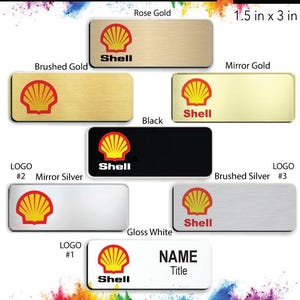 May include: A variety of name badges featuring the Shell logo in different colors and finishes, including brushed gold, mirror gold, black, mirror silver, brushed silver, and gloss white. The badges are 1.5 inches by 3 inches and come with a free pin back.