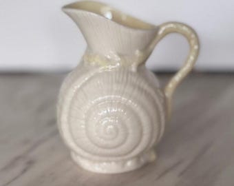 Cremeira Belleek Neptune Shell em porcelana irlandesa Parian, cor marfim e amarelo.