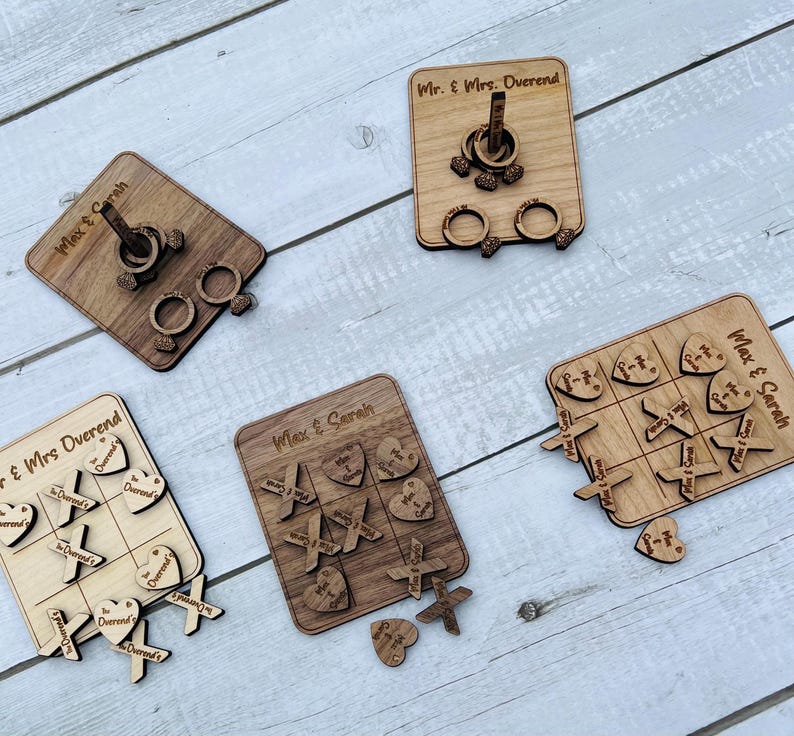 May include: A set of four wooden wedding games with personalized names. The games include a ring toss, a tic-tac-toe game, and a heart-shaped game. The games are made of natural wood and have a rustic look.