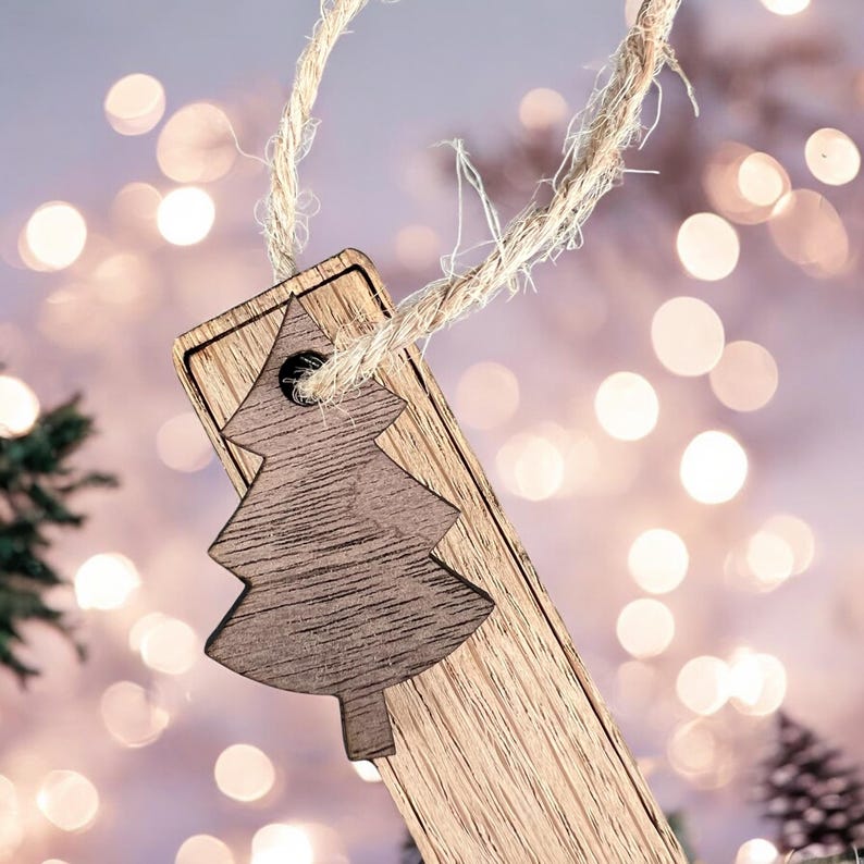 May include: A wooden Christmas tree ornament with a brown woodgrain finish and a cutout of a Christmas tree. The ornament is hanging from a twine string.