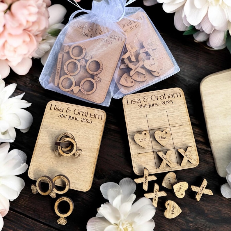 Puede incluir: Conjunto de juegos de boda de madera con tres juegos diferentes: un juego de lanzamiento de anillos, un juego de tres en raya y un juego con corazones y cruces. Los juegos est&aacute;n personalizados con los nombres "Lisa & Graham" y la fecha "31 de junio de 2025".