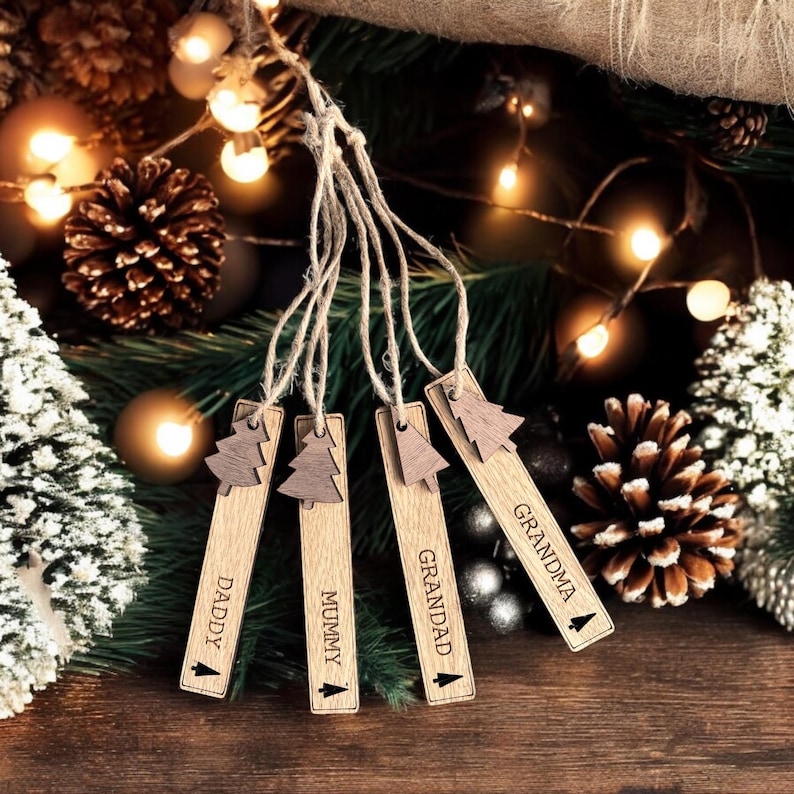 May include: Five wooden Christmas tree ornaments with twine hangers. Each ornament is engraved with a different name: "Daddy", "Mummy", "Grandad", "Grandma", and "Grandad".