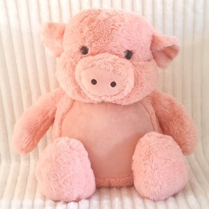 May include: A plush pink pig toy with a soft, fuzzy texture. The pig has a large, round head with black eyes and a small, pink snout.