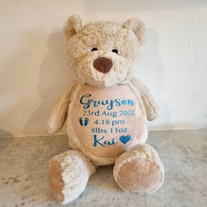 May include: A beige plush teddy bear with a personalized embroidered message on its chest. The message reads "Grayson 23rd Aug 2022 4.18 pm 8lbs 11oz Kai".