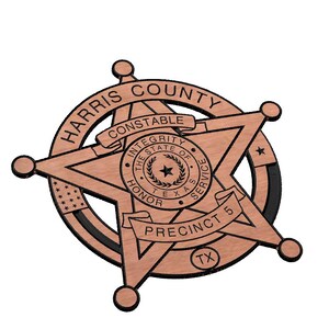 May include: A wooden badge with a five-pointed star in the center. The badge is brown and has black lettering. The text on the badge reads "Harris County Constable Precinct 5 TX" and "Integrity, Honor, The State of Texas, Service".