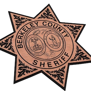 May include: A brown wooden star-shaped sheriff's badge with black lettering and a black outline. The badge says "Berkeley County Sheriff" and features two seals, one with a palmetto tree and the other with a person standing on a beach.