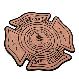 以下が含まれることがあります： 黒い輪郭のある木製の消防署のバッジ。バッジはマルタ十字の形をしており、「Summerville Fire Rescue」と「Est. 1894」の文字が書かれています。