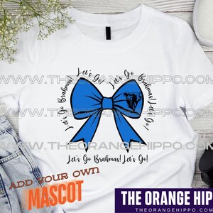 May include: White t-shirt featuring a large blue bow graphic with the text "Let's Go Brahmas!" in a circular design. The shirt also includes the text "Let's Go Brahmas! Let's Go!" and "Add Your Own Mascot".