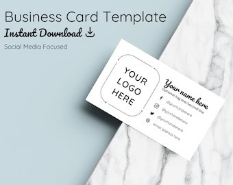 Könnte beinhalten: Eine weiße Visitenkartenvorlage mit einem schwarzen Rahmen um den Text "YOUR LOGO HERE". Die Karte enthält auch den Text "Your name here", "Optional tag line/second line" und Social-Media-Symbole mit Handles.