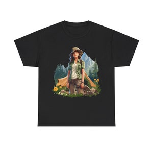 May include: A black t-shirt with a graphic of a woman in a forest setting. She is wearing a green shirt, khaki pants, and a hat. She is standing near a tent and some trees.
