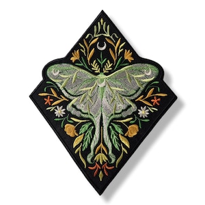 May include: Embroidered patch featuring a green moth with intricate wing details, surrounded by floral and leaf designs in yellow, orange, and white. The patch is set on a black, diamond-shaped background.
