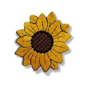 Può includere: Una toppa ricamata a forma di girasole con petali giallo vivace che si irradiano da un centro marrone scuro testurizzato. La cucitura crea un aspetto dettagliato e stratificato con linee distinte che definiscono ogni petalo.