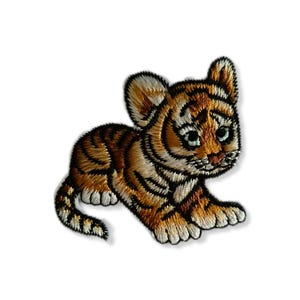 Peut inclure: Un petit patch brodé représentant un ourson tigre brun et orange avec des rayures noires. Le ourson est couché sur le ventre, la tête tournée sur le côté et les yeux fermés. Le patch est parfait pour ajouter une touche de fantaisie aux vêtements, sacs ou autres accessoires.