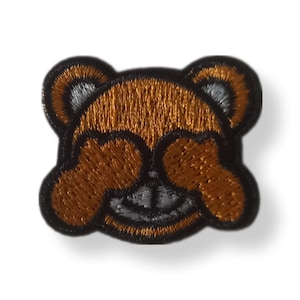 Peut inclure: Patch brodé thermocollant représentant un ours brun avec ses pattes qui lui cachent les yeux, souriant. Les yeux de l'ours sont blancs et la bouche est noire.