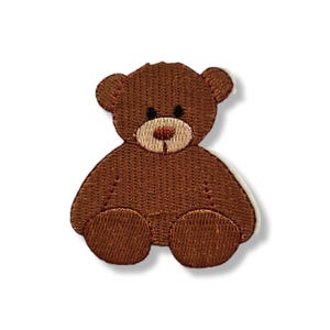 May include: A brown teddy bear patch with embroidered details. The bear has a light brown snout, black eyes, and a red nose. The patch is designed with a white border.