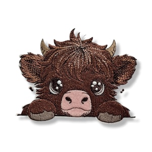 May include: Embroidered patch featuring a cartoon Highland cow with brown fur, large eyes, and a pink nose. The cow is peeking over a white surface, with its hooves visible. The patch has a detailed, textured appearance.