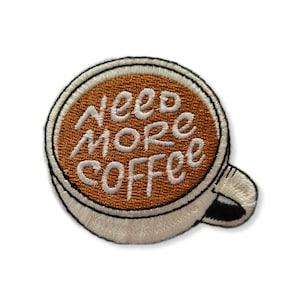 May include: Embroidered iron-on patch featuring a white coffee cup with the text "Need More Coffee" in white lettering on a brown background.