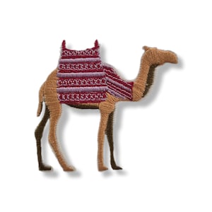 Puede incluir: Parche bordado de un camello de perfil, con pelaje marrón y beige y una silla decorativa roja y morada. El parche está cosido con detalle, resaltando la forma del camello y el diseño de la silla.