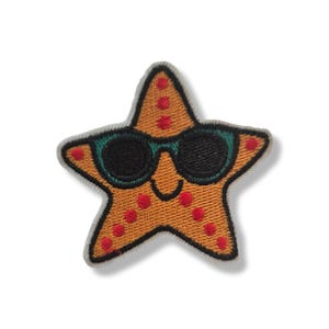 May include: Embroidered patch featuring an orange starfish with red spots and a grey border, wearing black sunglasses with green frames. A playful, beach-themed accessory for clothing or bags.