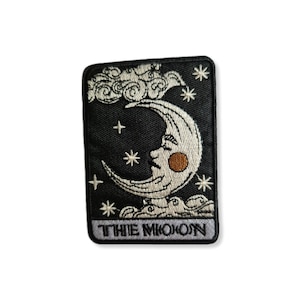 Peut inclure: Un patch brodé noir avec une lune croissante blanche avec un visage et un nuage au-dessus. Le texte "THE MOON" est en bas du patch.