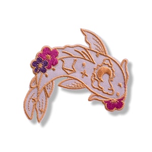 Op de afbeelding: Geborduurde patch met een gestileerd koi-visontwerp. De patch is lichtpaars met oranje contouren en accenten, waaronder bloemen in roze en paarse tinten. De vis heeft maan- en sterdetails.