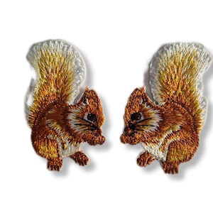 May include: Two embroidered iron-on patches of brown squirrels with white bushy tails. The squirrels are facing opposite directions.