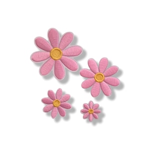 May include: Four embroidered flower patches in varying sizes, each featuring eight pink petals surrounding a circular yellow centre. The patches are arranged in a cluster, showcasing a consistent design with detailed stitching throughout the floral shapes.