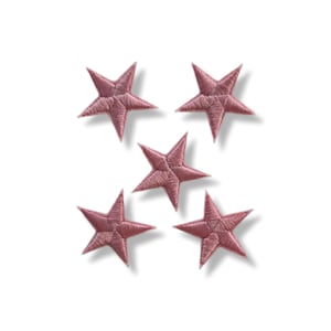 Puede incluir: Cinco parches bordados con forma de estrella en color rosa empolvado. Cada estrella tiene cinco puntas y está cosida con hilo texturizado. Los parches están dispuestos sobre un fondo blanco, con sombras sutiles.