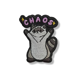Può includere: Toppa ricamata con un procione con le braccia alzate. Il procione è nei toni del grigio e del bianco, con un contorno nero. Sopra il procione, la parola "CHAOS" è ricamata in rosa, con stelle gialle.