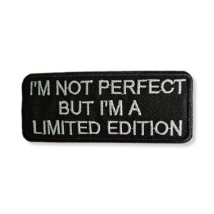 Pode incluir: Etiqueta bordada preta com texto branco que diz "Não sou perfeito, mas sou uma edição limitada."
