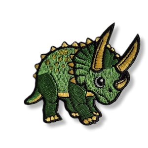 Può includere: Toppa ricamata verde da stirare con un dinosauro triceratopo dei cartoni animati con corna e accenti dorati.