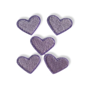 Pode incluir: Cinco patches em forma de coração de feltro roxo. Os patches têm aproximadamente 2,5 cm de diâmetro.
