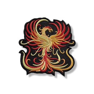 Puede incluir: Parche bordado con un diseño de fénix. El parche tiene un fondo negro con un fénix detallado en tonos de rojo, amarillo y dorado. El fénix está representado con las alas extendidas y una cola detallada.