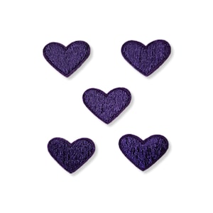 May include: Five purple felt heart patches. The hearts are all the same size and shape, and they are arranged in a random pattern.