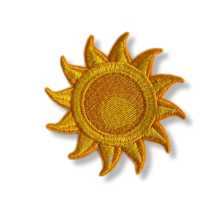 Peut inclure: Un écusson brodé jaune en forme de soleil avec un design détaillé. Le soleil a un centre jaune vif et des rayons d'une nuance de jaune légèrement plus foncée.