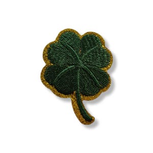Puede incluir: Parche bordado de trébol de cuatro hojas. El parche presenta un diseño de trébol verde oscuro con un borde dorado brillante. El trébol tiene costuras detalladas y un tallo. Para ropa o accesorios.