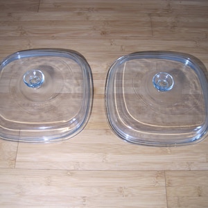Puede incluir: Dos tapas de vidrio transparente para una olla de cocción lenta cuadrada. Las tapas tienen un pequeño pomo en el centro.